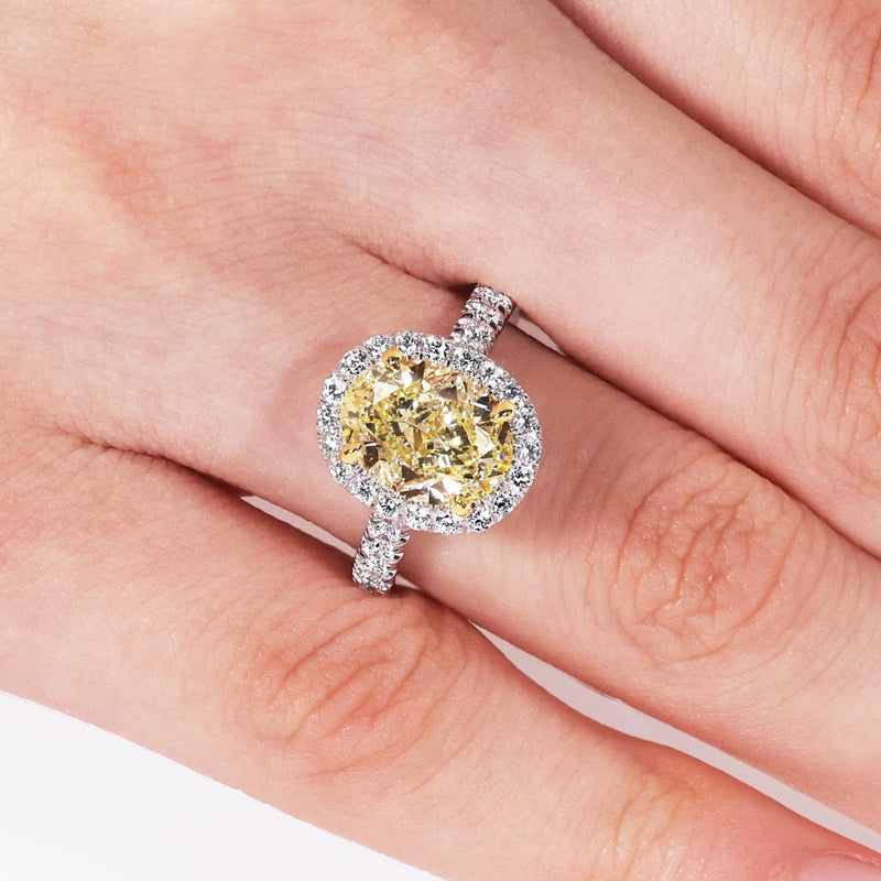 18ct white and yellow gold fancy yellow oval cut and white diamond halo engagement ring on the finger