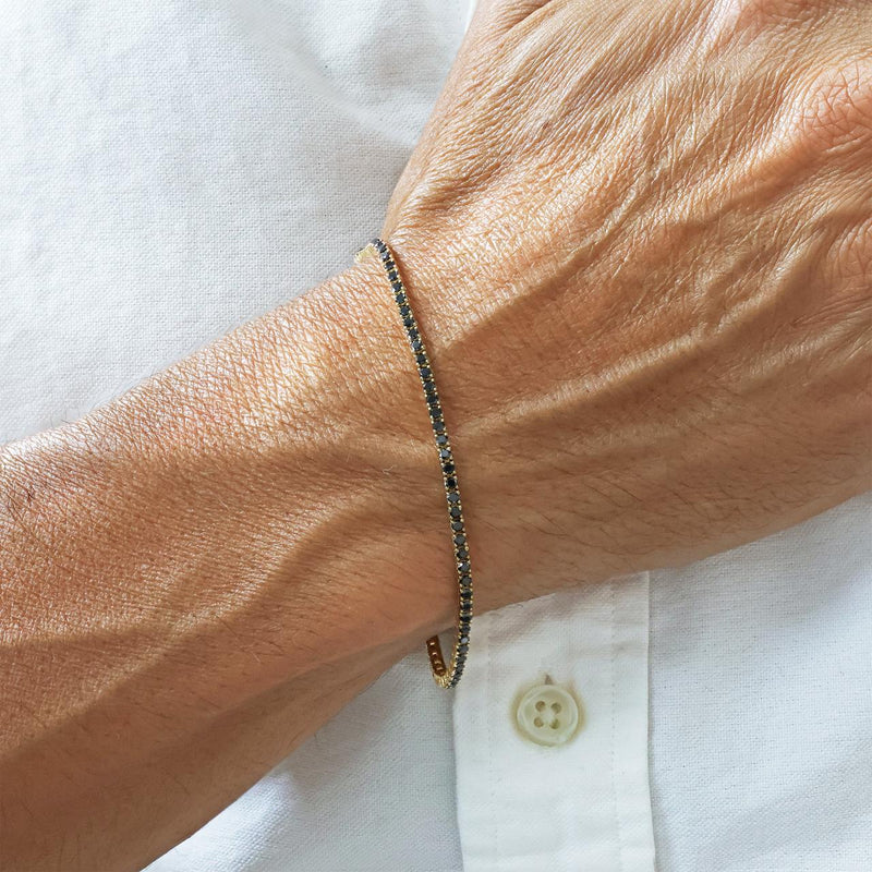 18ct yellow gold black round diamonds tennis bracelet in a four claw setting on wrist
