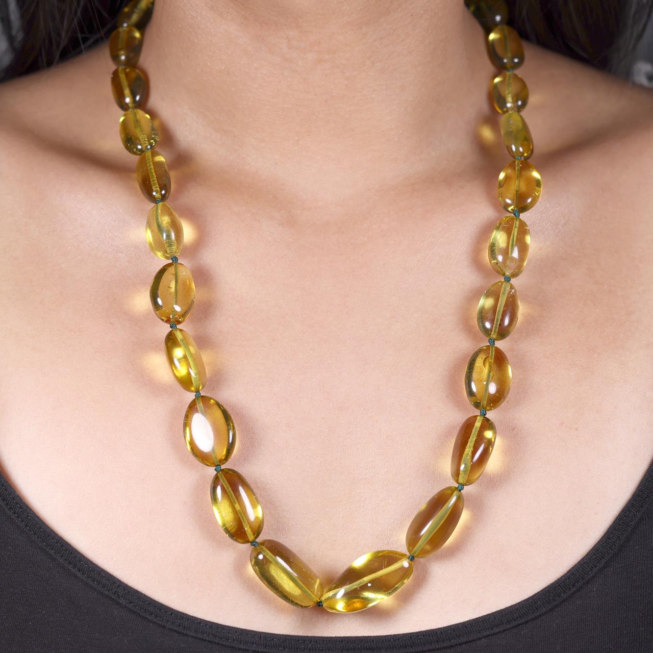 Green amber beads single row bracelet ending with a silver magnetic clasp from the Carmela Cerrone Collection on the neck
