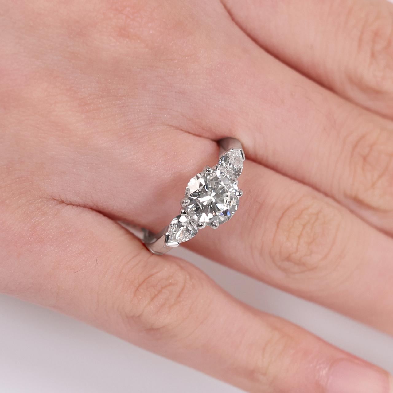 18ct white gold round brilliant cut diamond ring with pear shaped diamonds on the sides on the finger