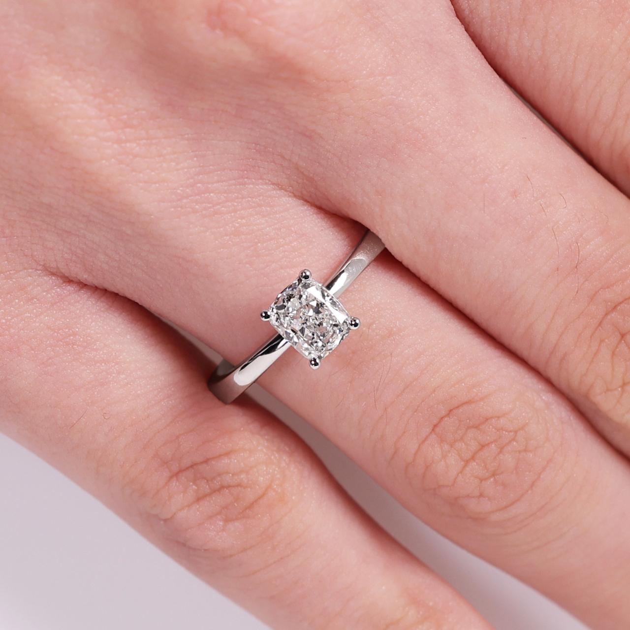 18ct white gold cushion cut diamond solitaire ring in a four claw setting on finger