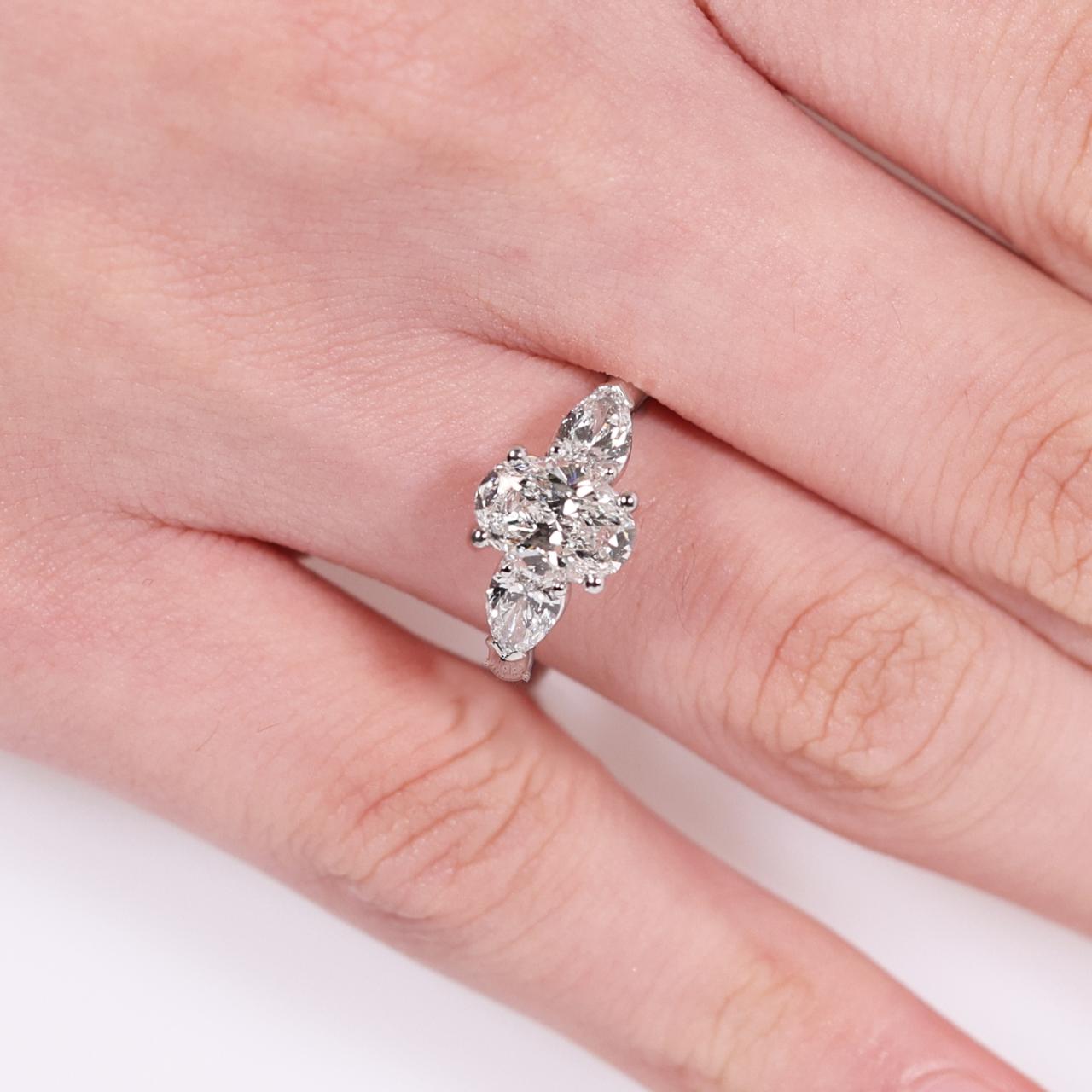 18ct white gold 1.20ct oval brilliant cut diamond and 2=0.60ct pear shaped diamonds ring on finger