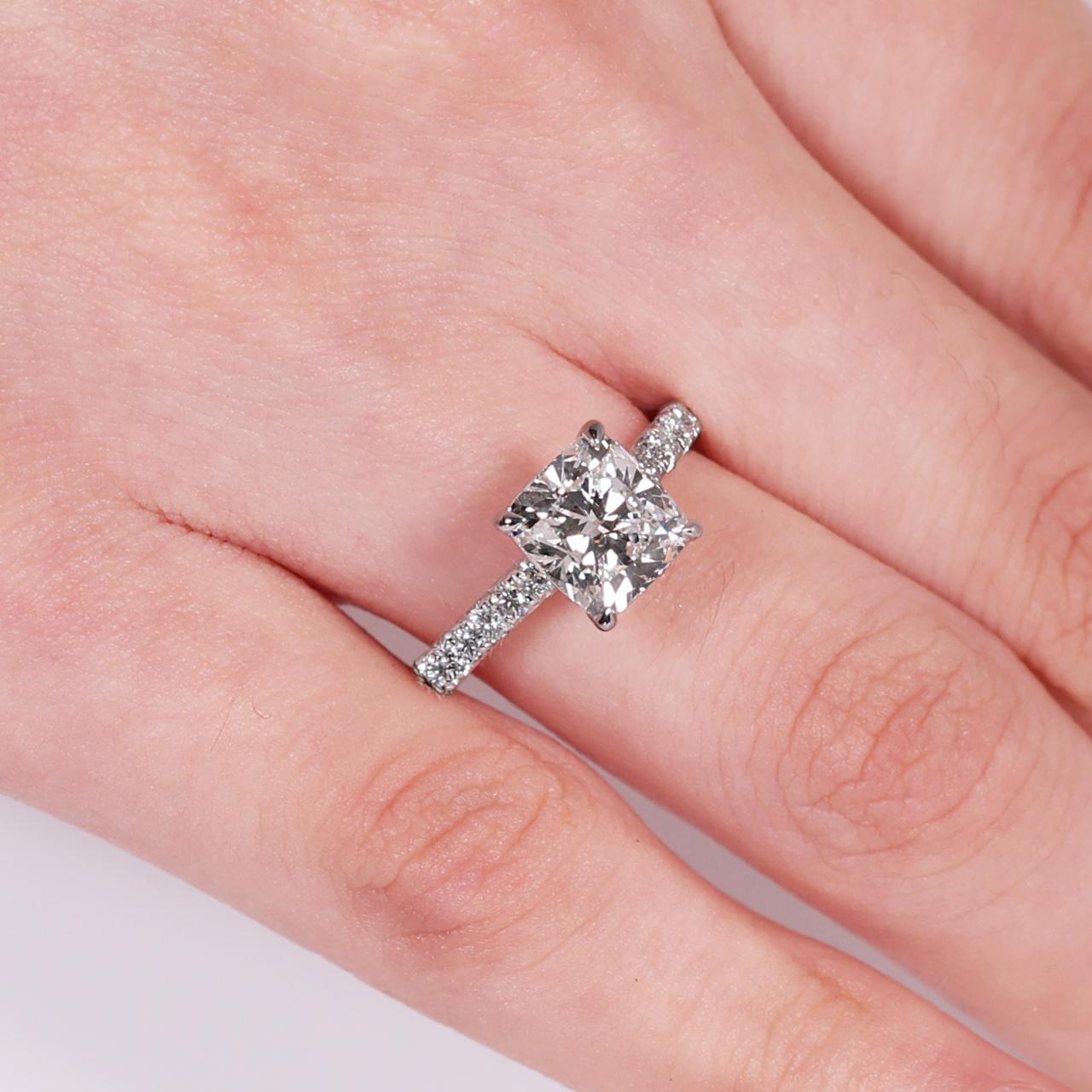 18ct white gold 2.02ct cushion cut diamond ring in a four claw setting with diamond band on finger