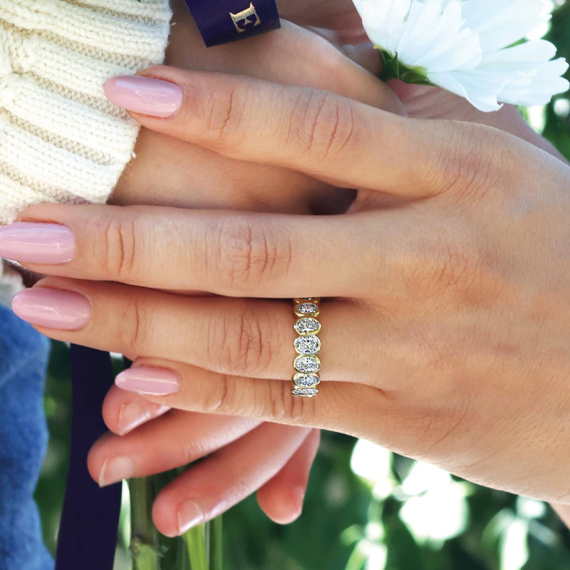 18ct yellow gold oval brilliant cut diamonds ring in a bezel setting on the finger