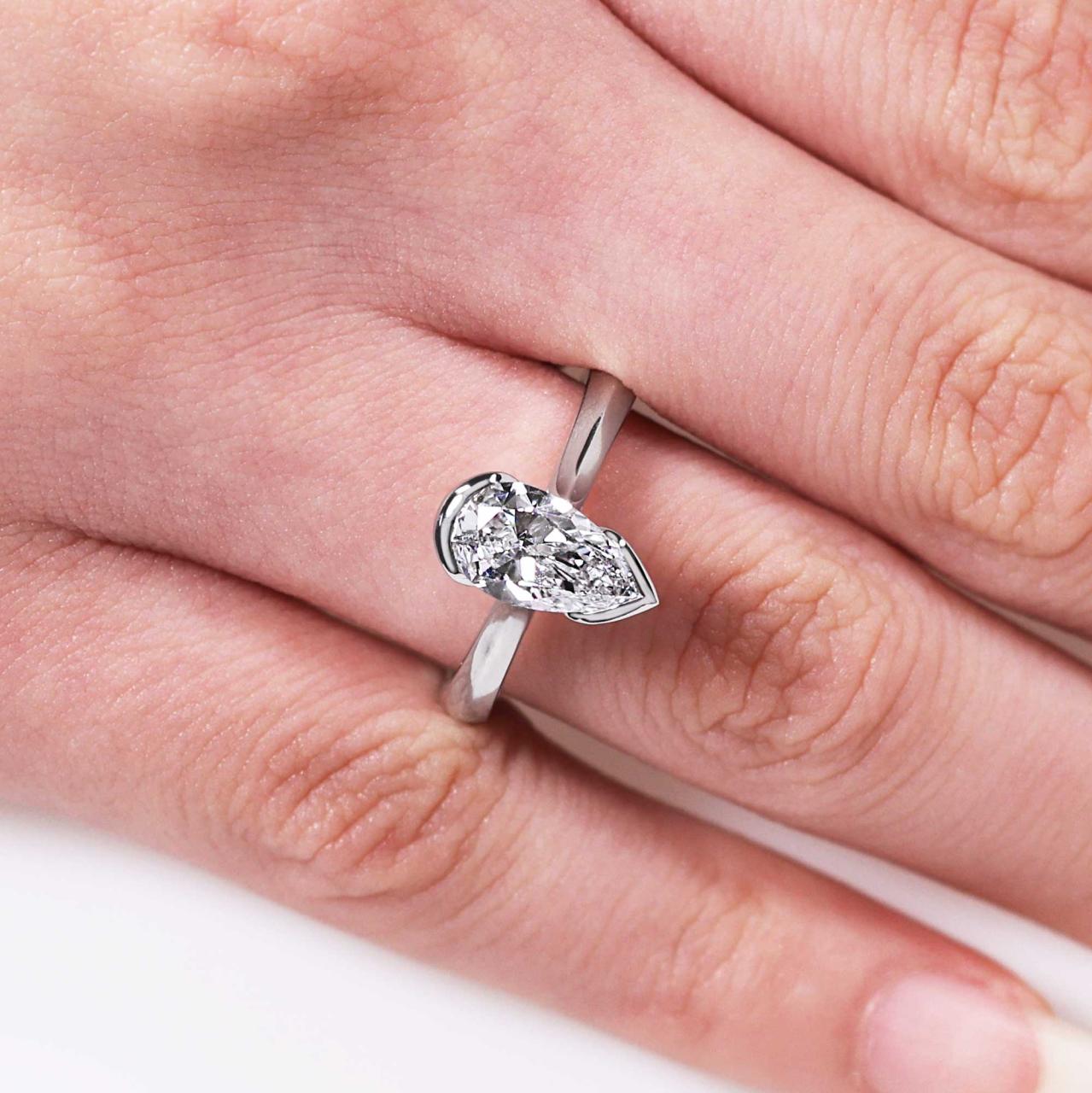 Platinum gold 1.40ct D VVS2 pear shaped lab grown diamond solitaire engagement ring in a half bezel setting. IGI Cert