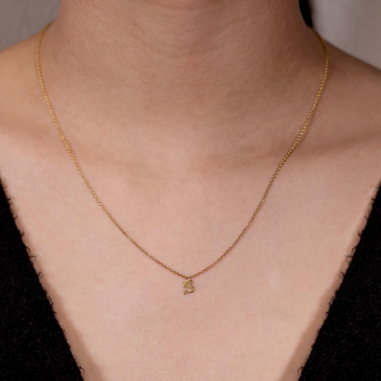 18ct yellow gold initial "S" necklace on the neck