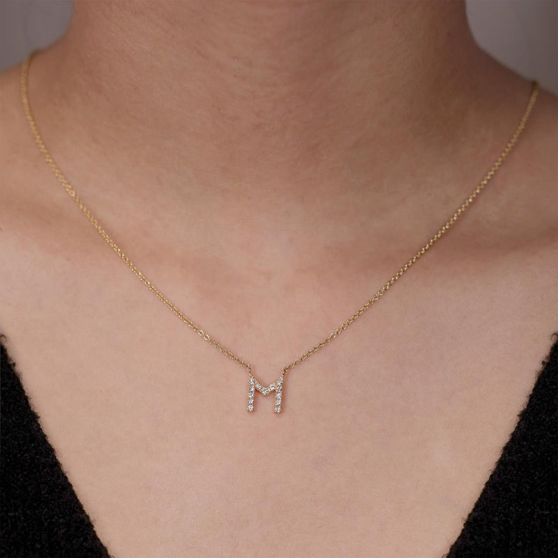 18ct yellow gold diamond initial "M" necklace on the neck