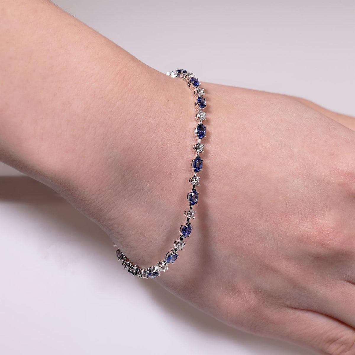 18ct white gold oval Ceylon sapphires and round brilliant cut diamonds tennis bracelet on the wrist