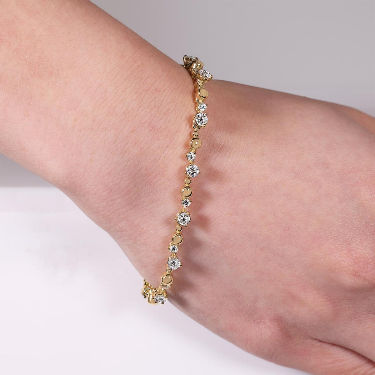 18ct yellow gold 16=1.96ct DEF VVS VS round brilliant cut Lab grown diamonds tennis bracelet in a three claw setting on the wrist